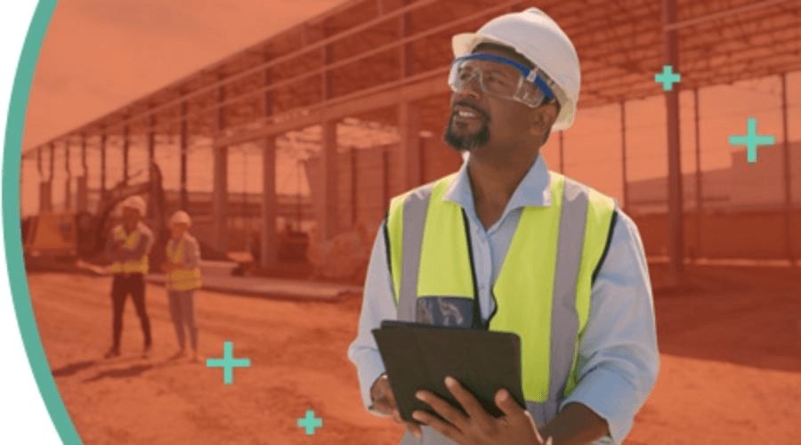 Supervisor wearing a high-visibility safety vest and hard hat, holding a tablet at a construction site.
